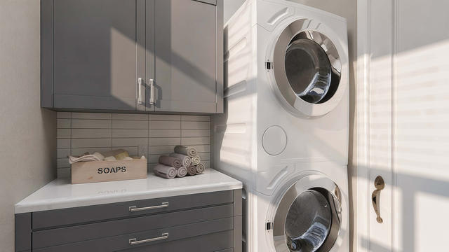 Interior rendering of the laundry room showing stacked appliances, wall cabinets, counter space, and utility storage