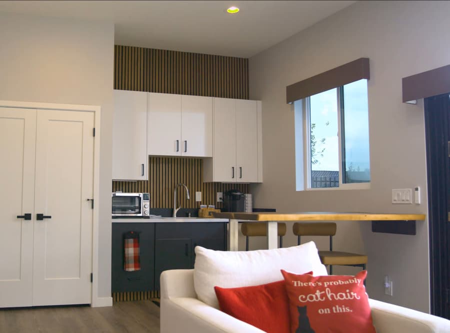 Buckeye studio casita kitchenette with gray cabinets, white uppers, closet doors, and living area seating