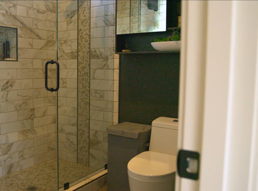 Buckeye studio casita bathroom shower with stone-look tile, black fixtures, and glass door