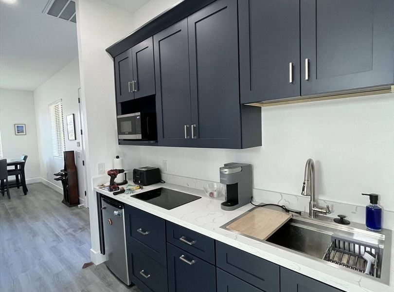 Cave Creek casita ADU kitchenette with dark blue cabinets, compact appliances, and quartz-look counter