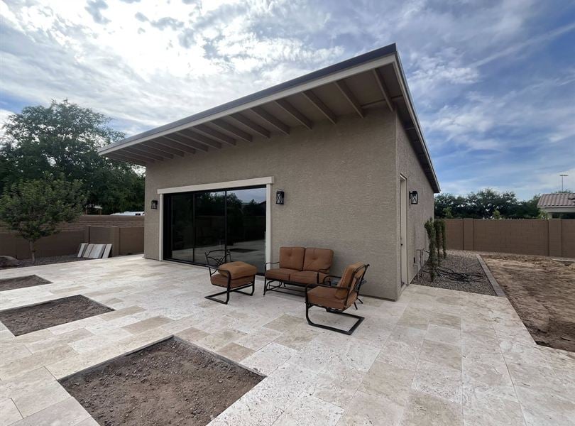 Queen Creek pool house exterior with patio seating, stucco finish, and large sliding glass door