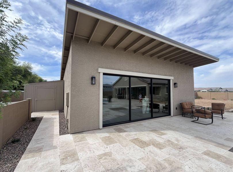 Angled exterior view of Queen Creek pool house with patio pavers and outdoor seating