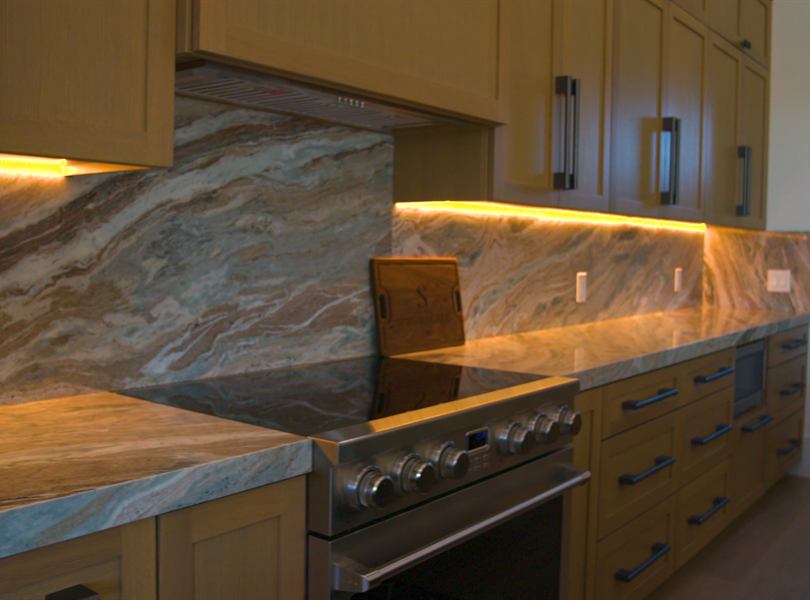 Custom casita kitchen with stone backsplash and warm cabinetry
